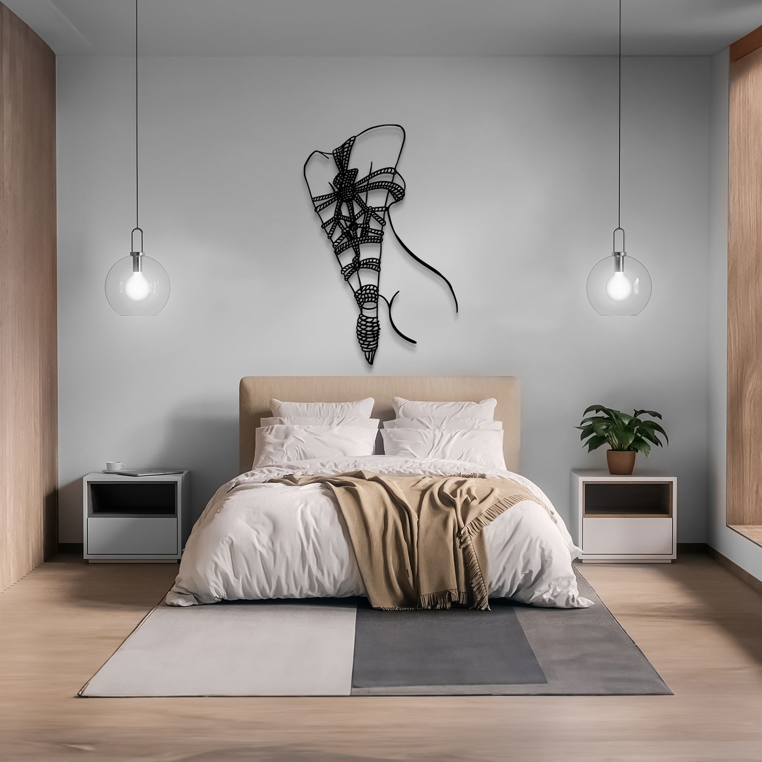 A modern bedroom scene with a bed dressed in white bedding and a beige throw blanket, centered against a light gray wall. A black wire elephant wall art piece hangs above the bed.
