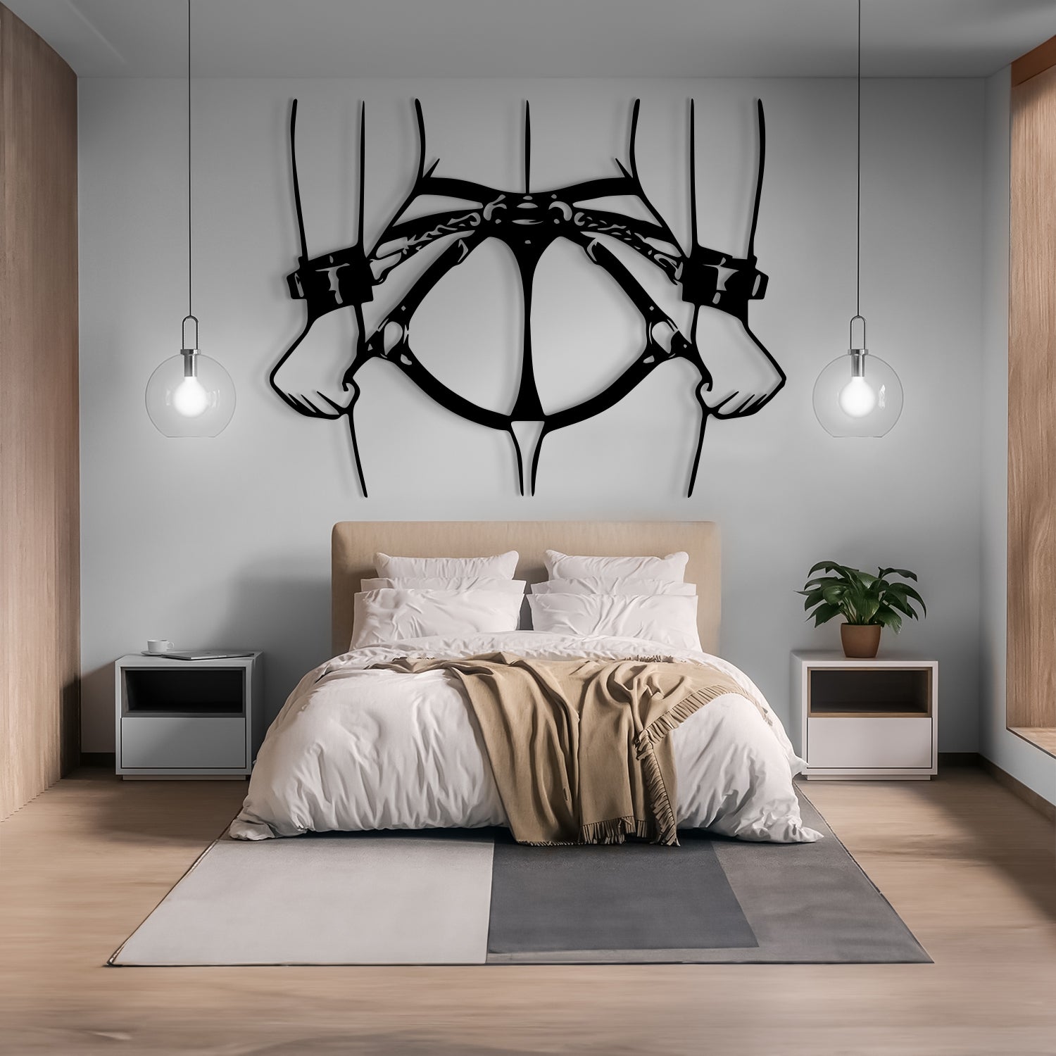 A modern bedroom interior with a bed dressed in white bedding and a beige throw blanket, flanked by two white nightstands. Above the bed hangs a large black metal wall sculpture shaped like hands holding up a harness.