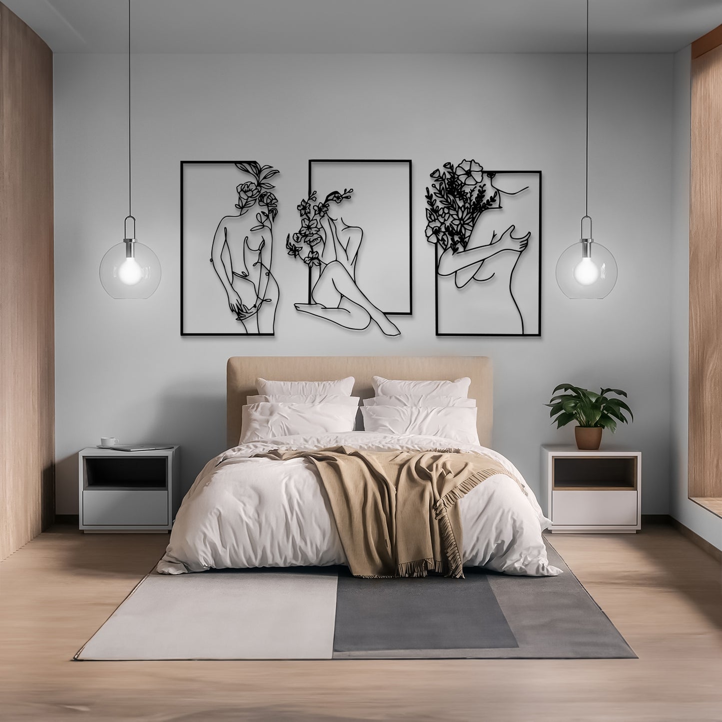 A modern bedroom with a beige upholstered bed, white bedding, a tan throw blanket, two white nightstands, pendant lights, and three black framed wall art pieces above the bed. The room has light gray walls and wood flooring.
