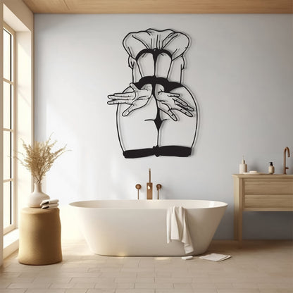 A black metal wall art piece depicting a stylized figure with hands behind the back, mounted on a light gray wall above a white freestanding bathtub in a modern bathroom setting.