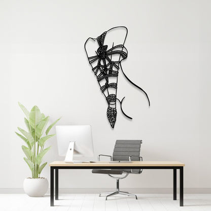 A black metal wall art sculpture of a stylized bow and arrow hangs on a light gray wall above a modern desk setup with a computer monitor, chair, and potted plant.