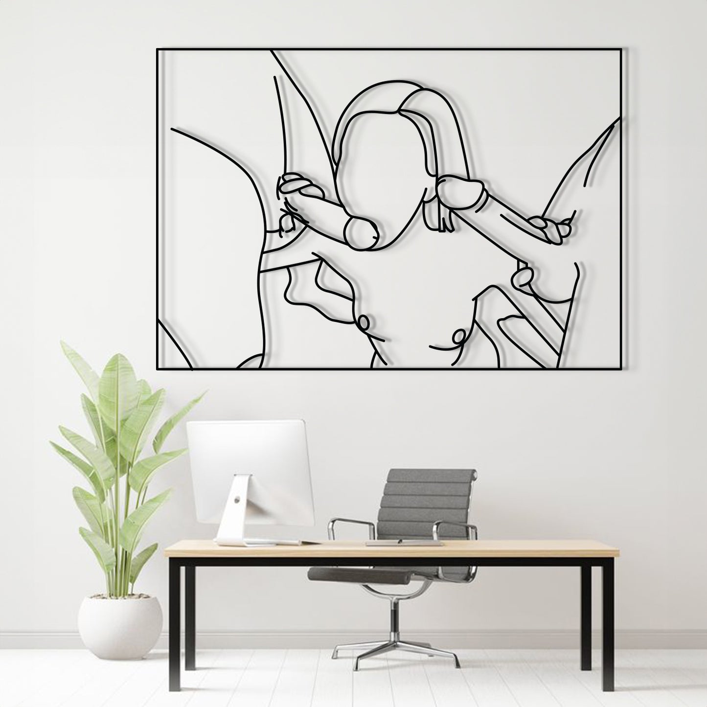 A minimalist black and white continuous line art print of a woman is displayed on a white wall above a modern desk setup with a computer, office chair, and a potted plant.