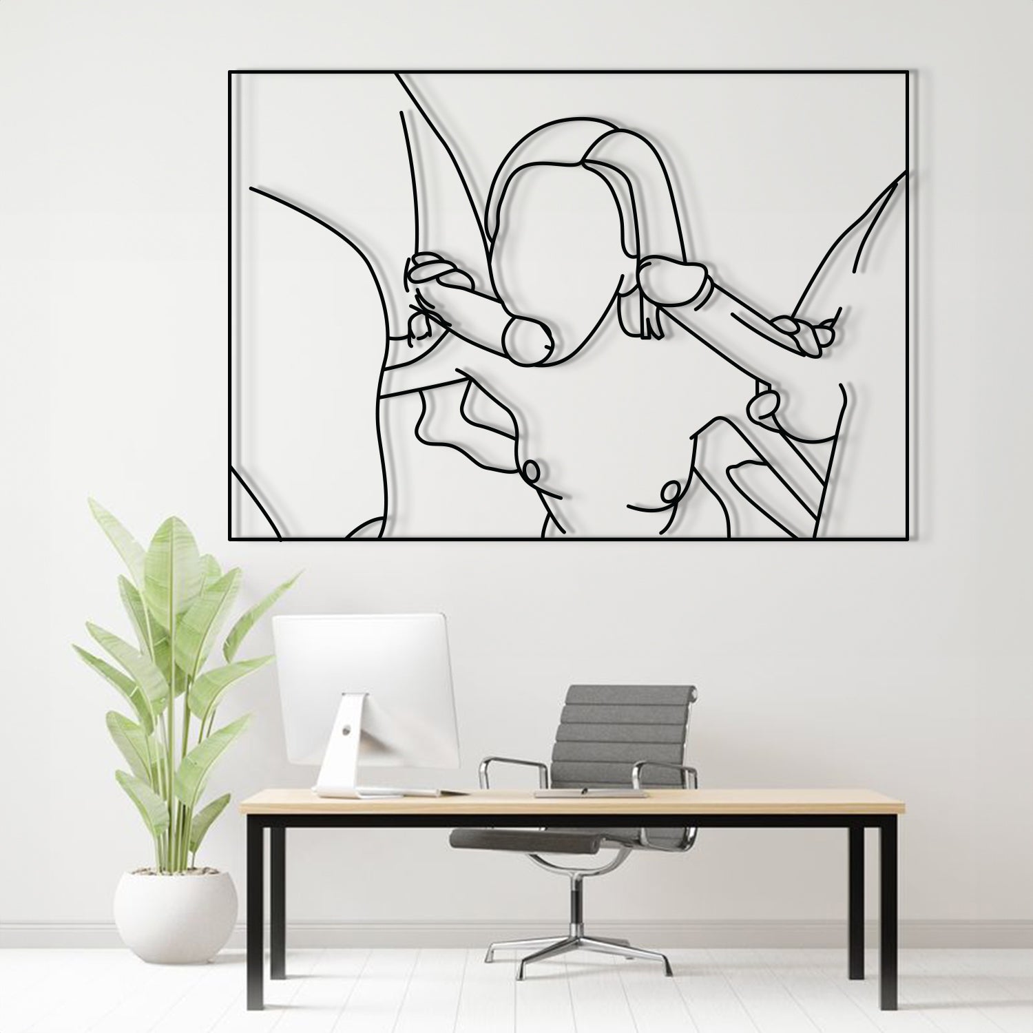 A minimalist black and white continuous line art print of a woman is displayed on a white wall above a modern desk setup with a computer, office chair, and a potted plant.