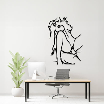 A black line art wall decal of a dog sitting and being scratched by a cat, displayed on a light gray wall above a modern desk setup with a computer, chair, and potted plant.