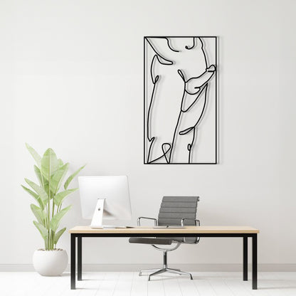 A minimalist black line art metal wall art print hangs on a white wall above a modern desk setup with a computer, office chair, and a potted plant.