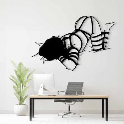 A black metal wall art sculpture of a woman in a bikini floating on her knees, displayed above a modern desk setup in a bright, minimalist office room.