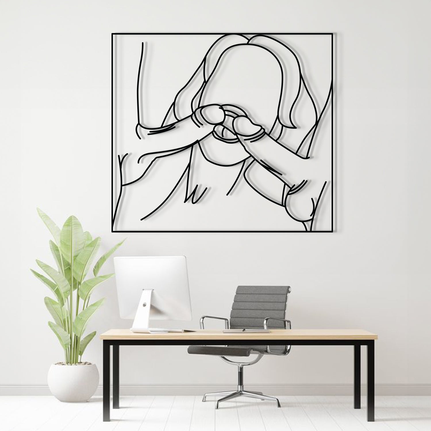 A minimalist black and white continuous line art print of a person covering their face, displayed on a white wall above a modern desk setup with a computer, chair, and a potted plant.