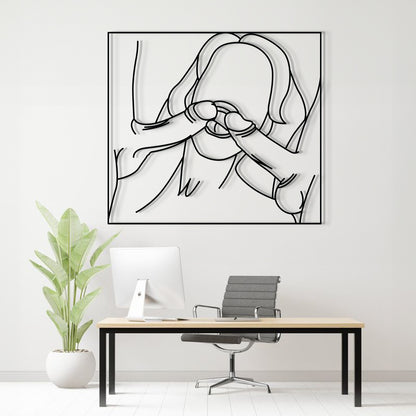 A minimalist black and white continuous line art print of a person covering their face, displayed on a white wall above a modern desk setup with a computer, chair, and a potted plant.