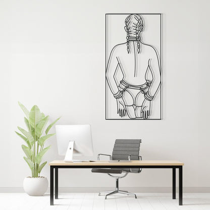 A minimalist black and white line art poster of a woman's back with braids, displayed on a white wall above a modern desk setup with a computer, chair, and potted plant.