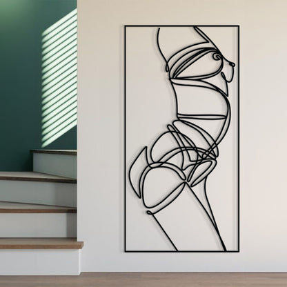 A tall black-and-white abstract line art print or wall sculpture mounted on a white wall in a modern interior with visible stairs and green wall panels.