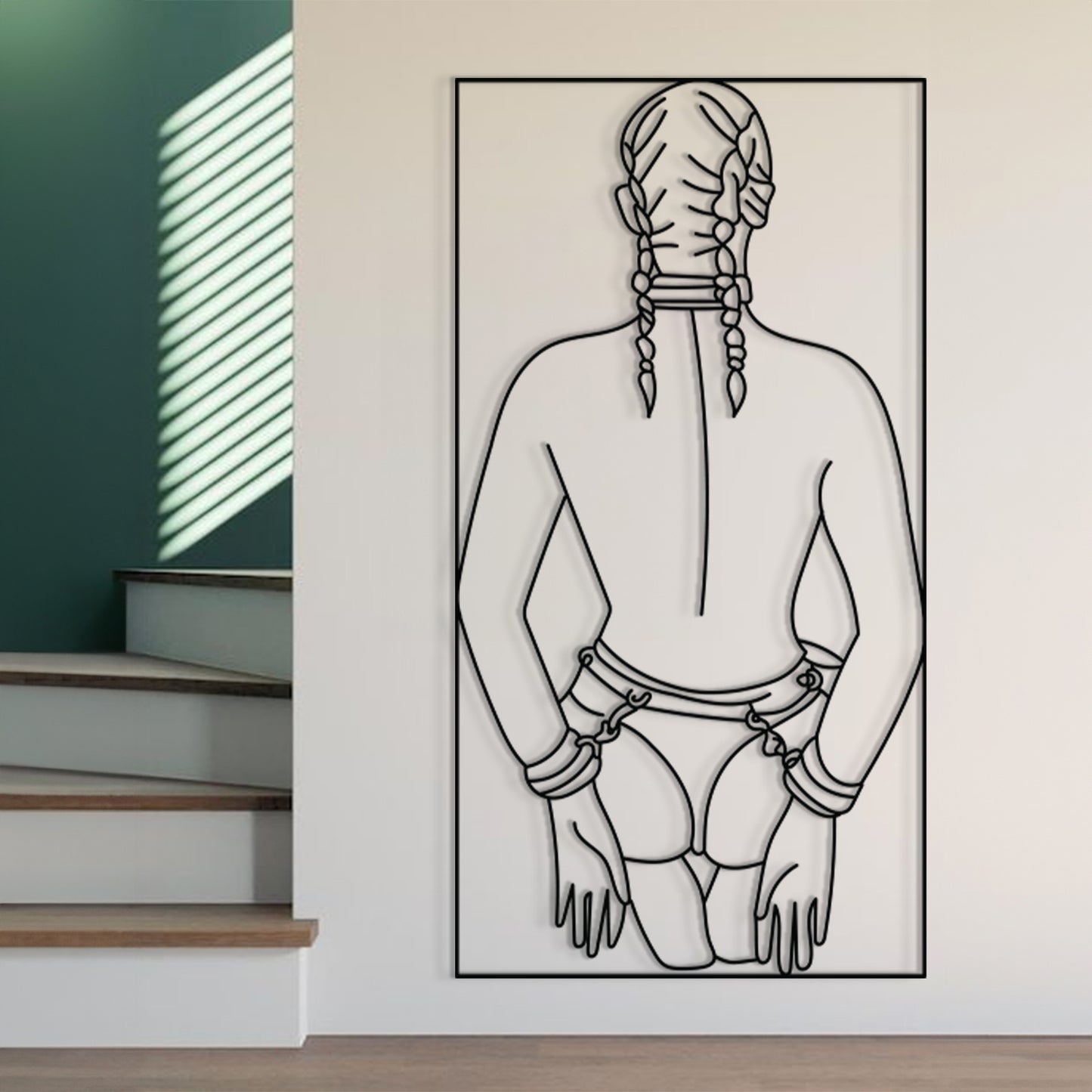 A large black and white line art print of a kneeling figure with braided hair, shown hanging on a white wall in a modern interior setting with stairs and window blinds visible.