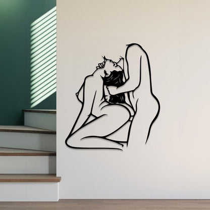 Black minimalist line art wall decal of an embracing couple, shown mounted on a white interior wall next to a staircase.