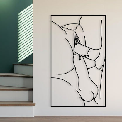 A minimalist black and white continuous line art print depicting a couple embracing, displayed on a light beige wall in a modern interior setting with wooden stairs and green walls in the background.