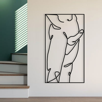 A minimalist black and white continuous line art print of a pregnant woman, displayed on a light beige wall in a modern interior setting with wooden stairs and green walls visible.