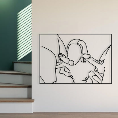 A minimalist black and white continuous line art print of a couple embracing, displayed on a white wall in a modern interior setting with a staircase and green accent wall visible.