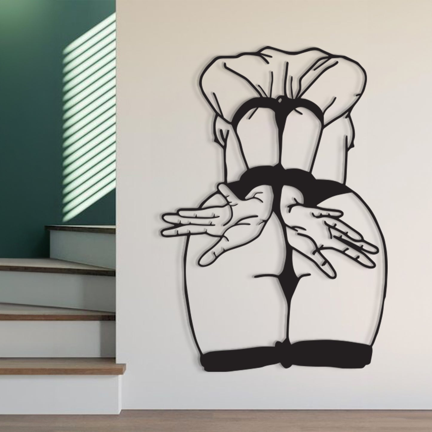 Black and white wall art depicting a stylized rear view of a person in a ruffled top and black underwear, mounted on a white wall in a modern interior setting with stairs and window blinds visible.