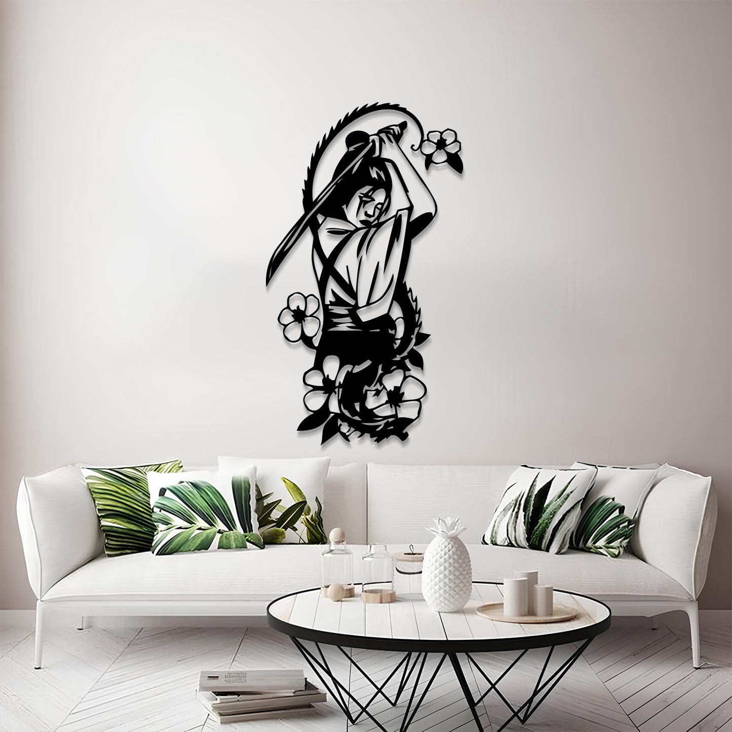 A black metal wall art piece depicting a samurai warrior with a sword and surrounding flowers, mounted on a light gray wall above a modern white sofa with green leaf-patterned pillows.