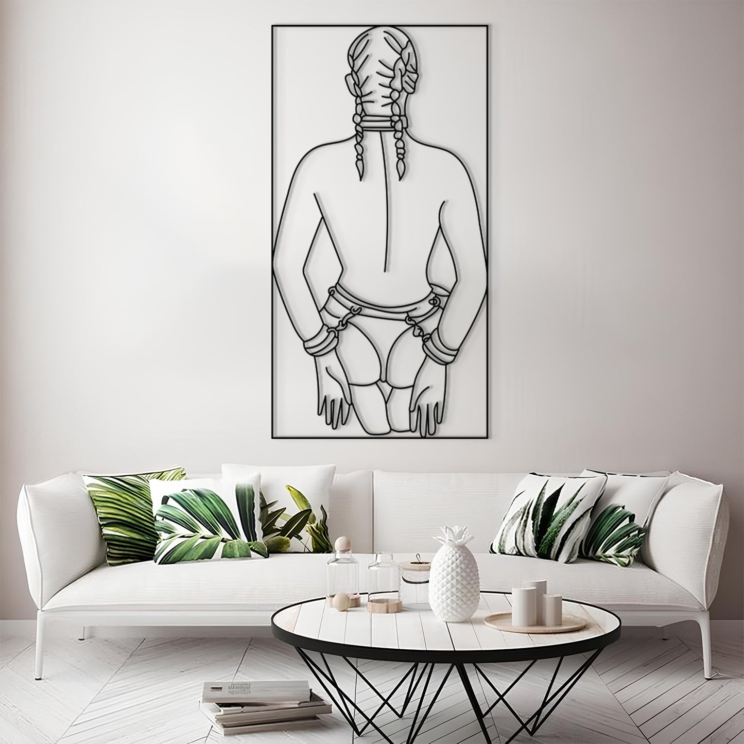 A modern living room scene featuring a large black and white minimalist line art print of a person with braided hair on the wall above a white sofa with green leaf-patterned pillows.