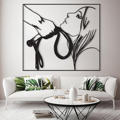 A large black and white minimalist wall art print depicting a woman's profile and a hand holding a snake, displayed above a white sofa in a modern living room setting.