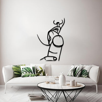 A minimalist black metal wall art piece depicting an abstract bull, displayed on a light gray wall above a modern white sofa with green leaf-patterned pillows.