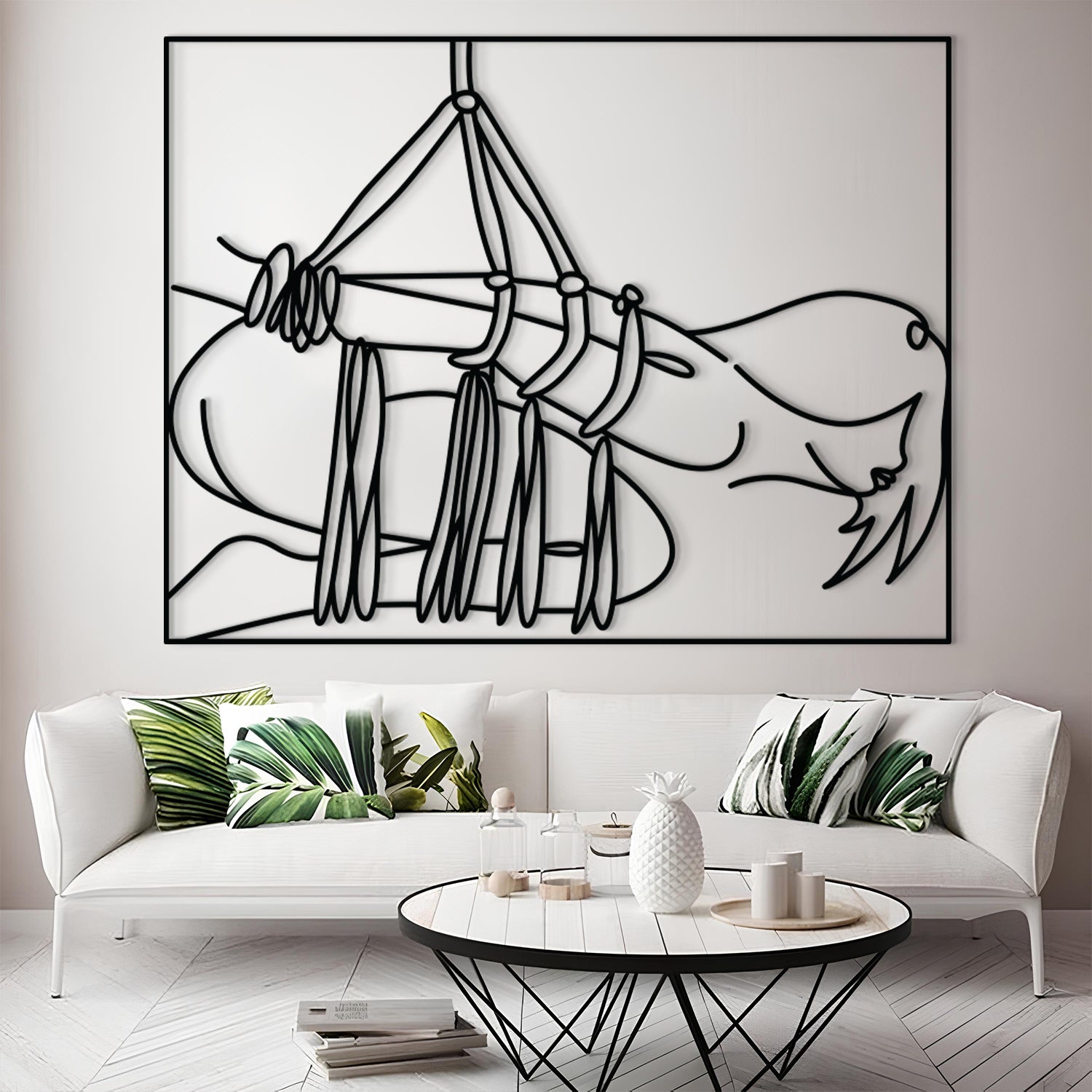 A large black and white minimalist line art print of a hammock hanging above a white sofa in a modern living room setting.