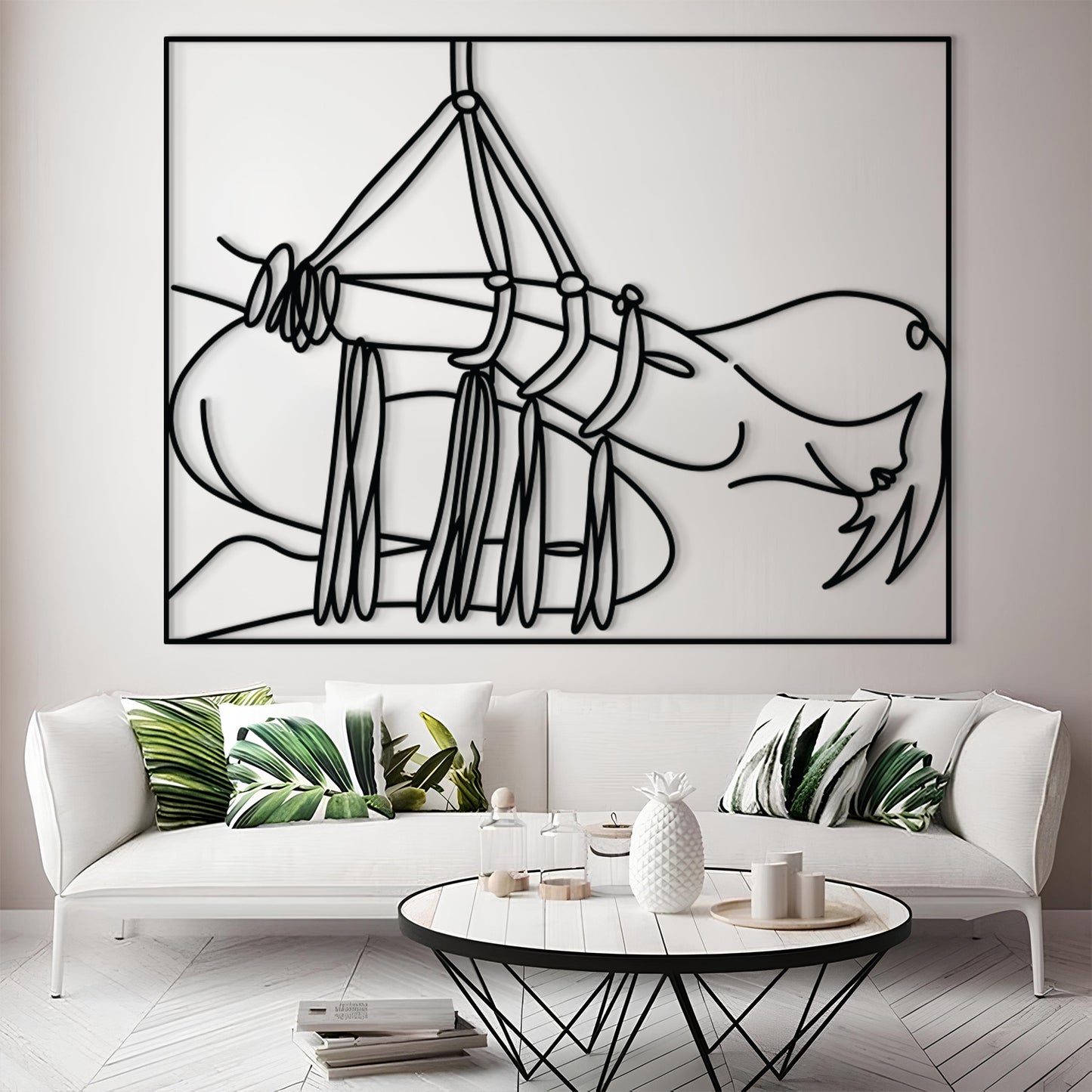 A large black and white minimalist line art print of a hammock hanging above a white sofa in a modern living room setting.