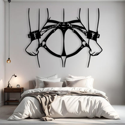 A large black metal wall art piece depicting a harness or collar design hangs above a neatly made bed in a modern bedroom setting.