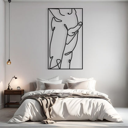 A minimalist black and white continuous line art print of a female torso, displayed in a modern bedroom setting above a neatly made bed.